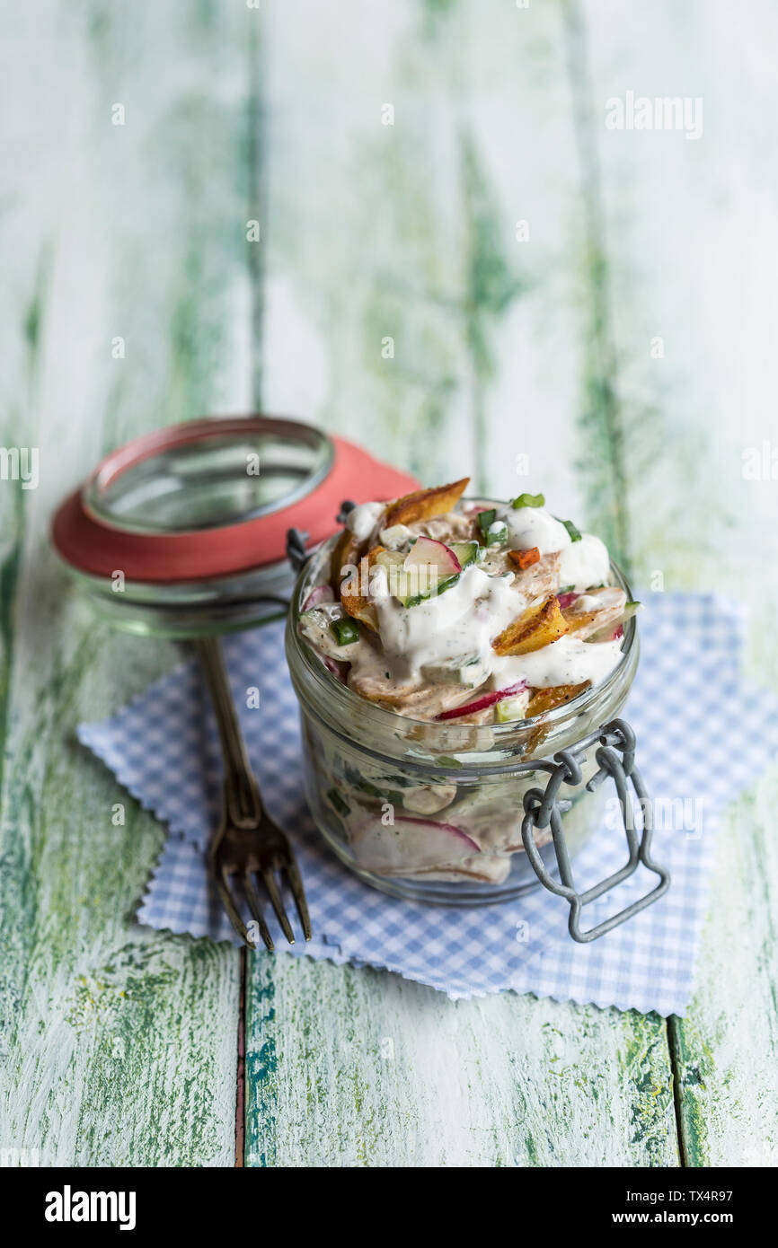 Glas gebratener Kartoffelsalat mit Gurke, rote Radieschen, Frühlingszwiebeln und Mayonnaise Joghurt Dressing Stockfoto