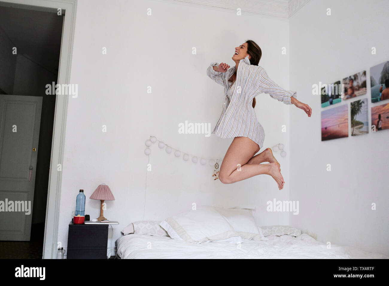 Junge Frau vor Freude hüpfend auf ihrem Bett Stockfoto