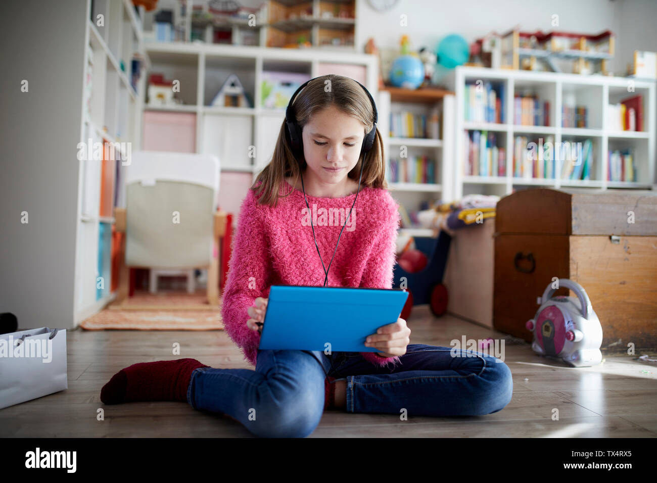 Junges Mädchen mit digitalen Tablet mit Kopfhörer, sitzen auf dem Boden Stockfoto