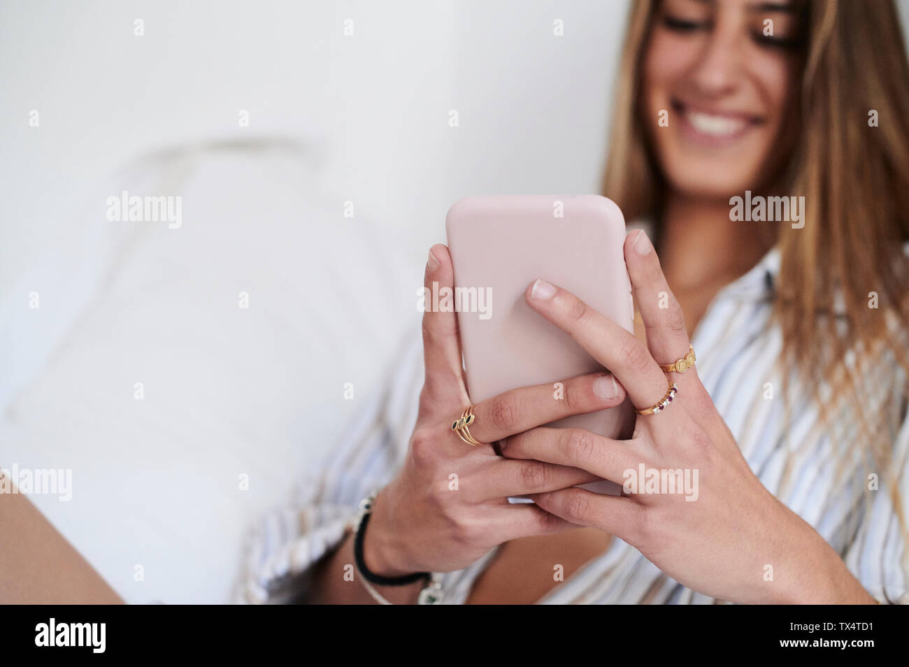 Junge Frau sitzt auf dem Bett, sie ihr Smartphone Stockfoto