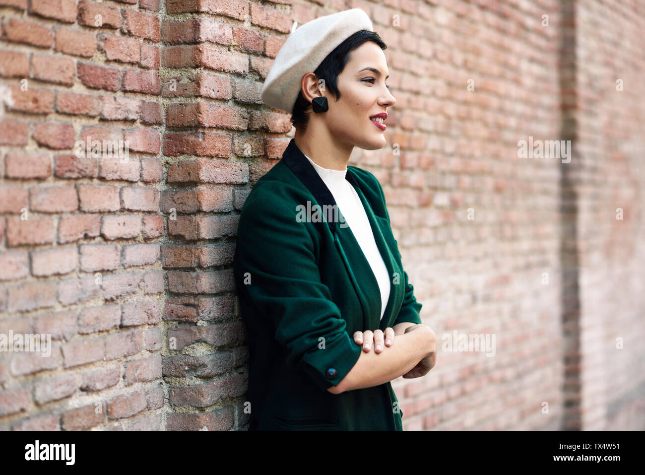 Modische junge Frau das Tragen einer Baskenmütze und eine grüne Jacke an  eine Wand Stockfotografie - Alamy