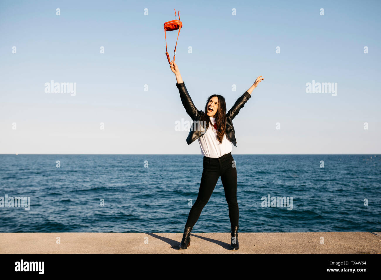 Glückliche Frau spielen mit roten Tasche, das Meer im Hintergrund Stockfoto