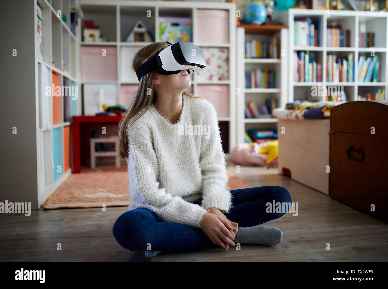 Mädchen in ihrem Zimmer sitzen, mit VR-Brille Stockfoto