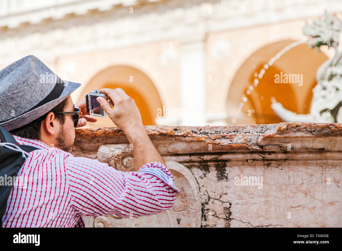 Italien, Marken, Loreto, Mitte erwachsener Reisender mit Action Cam an einem Brunnen Stockfoto