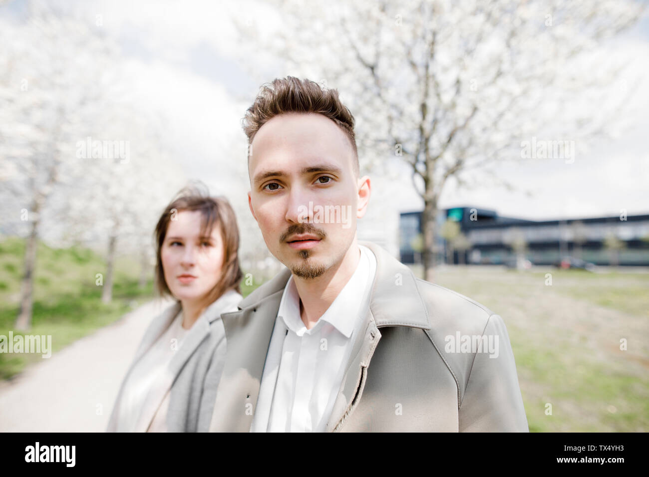 Porträt eines jungen Mannes mit Freundin im Hintergrund, ina Park im Frühling Stockfoto