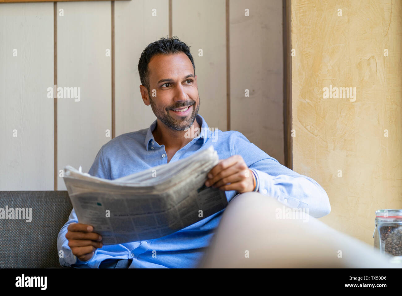 Lächelnd Geschäftsmann sitzen unten lesen Zeitung Stockfoto