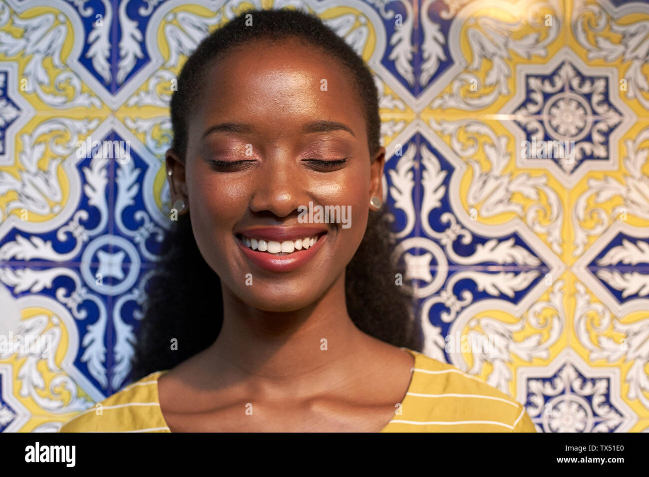 Portrait eines glücklichen jungen Frau an einem gefliesten Wand Stockfoto