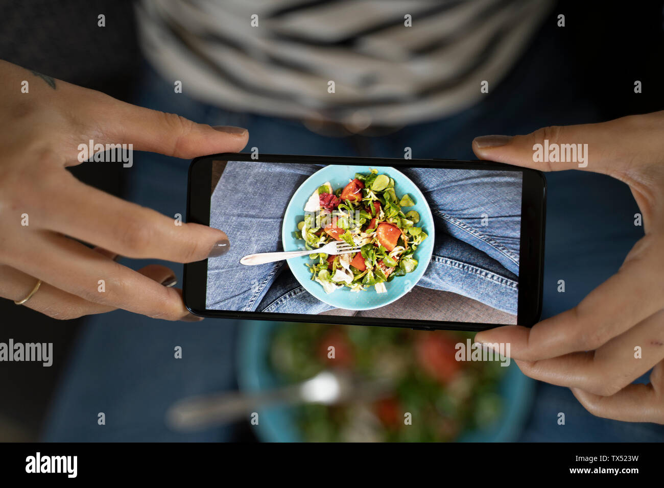 Woman's Hände halten Smartphone, wobei Bild von Salat Stockfoto