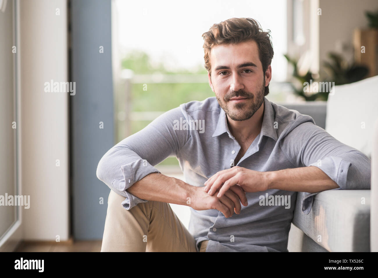 Portrait des jungen Mannes in seinem Wohnzimmer sitzen Stockfoto