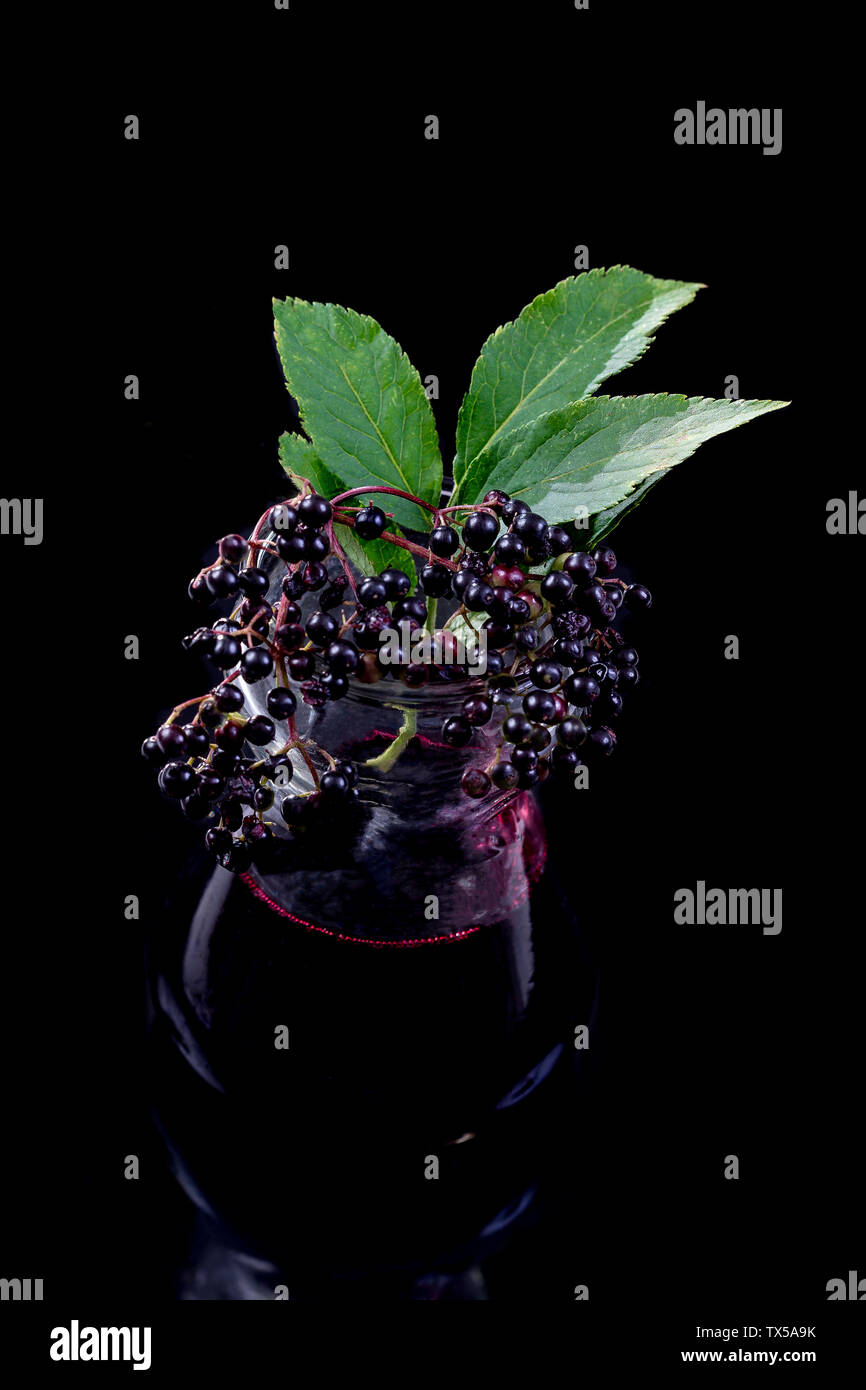 Holundersaft.jar an hausgemachten Holundersaft und frische Früchte auf schwarzem Hintergrund Stockfoto