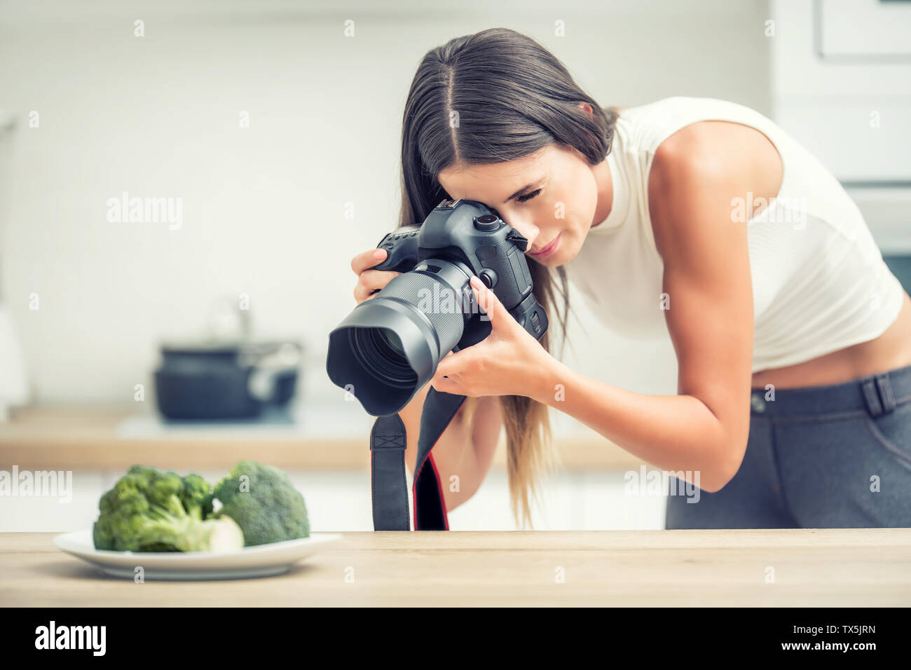 Frau Gewerbsmäßiges Fotografieren Platte mit Brokkoli. Essen Fotograf arbeiten in Küche Studio. Stockfoto