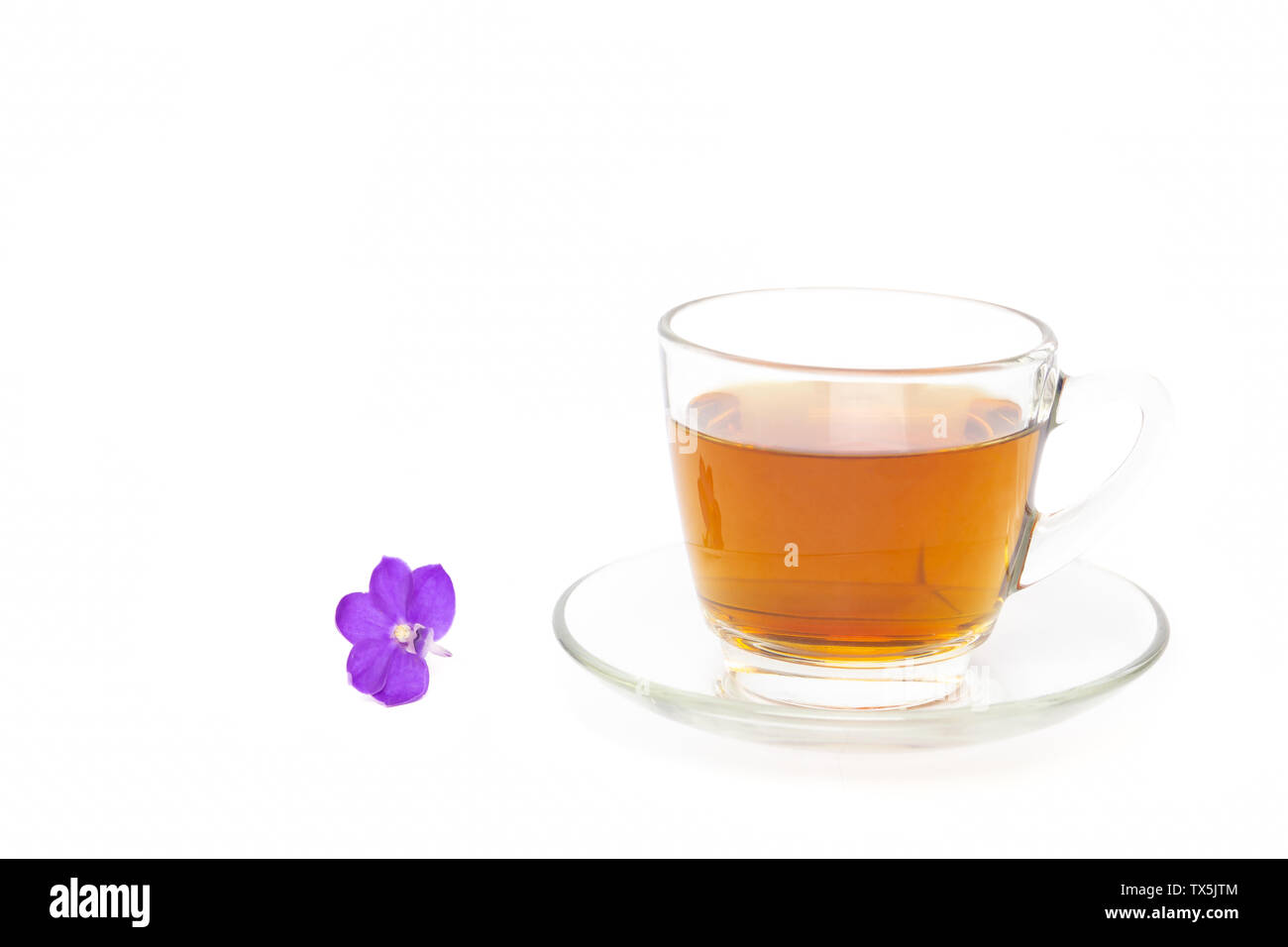 Tee in ein Glas Schale mit lila Blumen auf weißem Hintergrund. Stockfoto