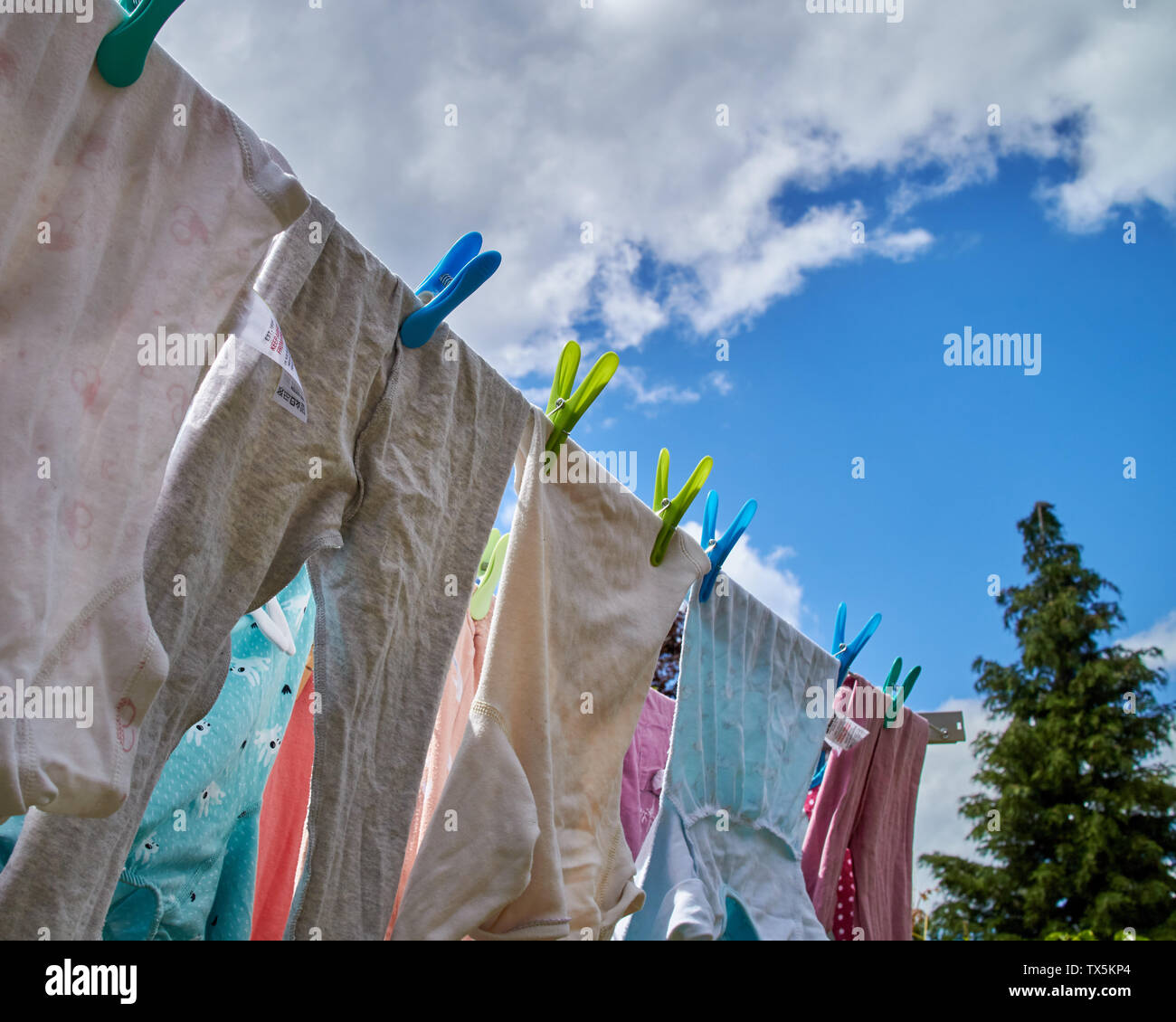 Kleidung durch Pflöcke trocknen auf der Wäscheleine hing, an einem lebendigen Sommer. Stockfoto
