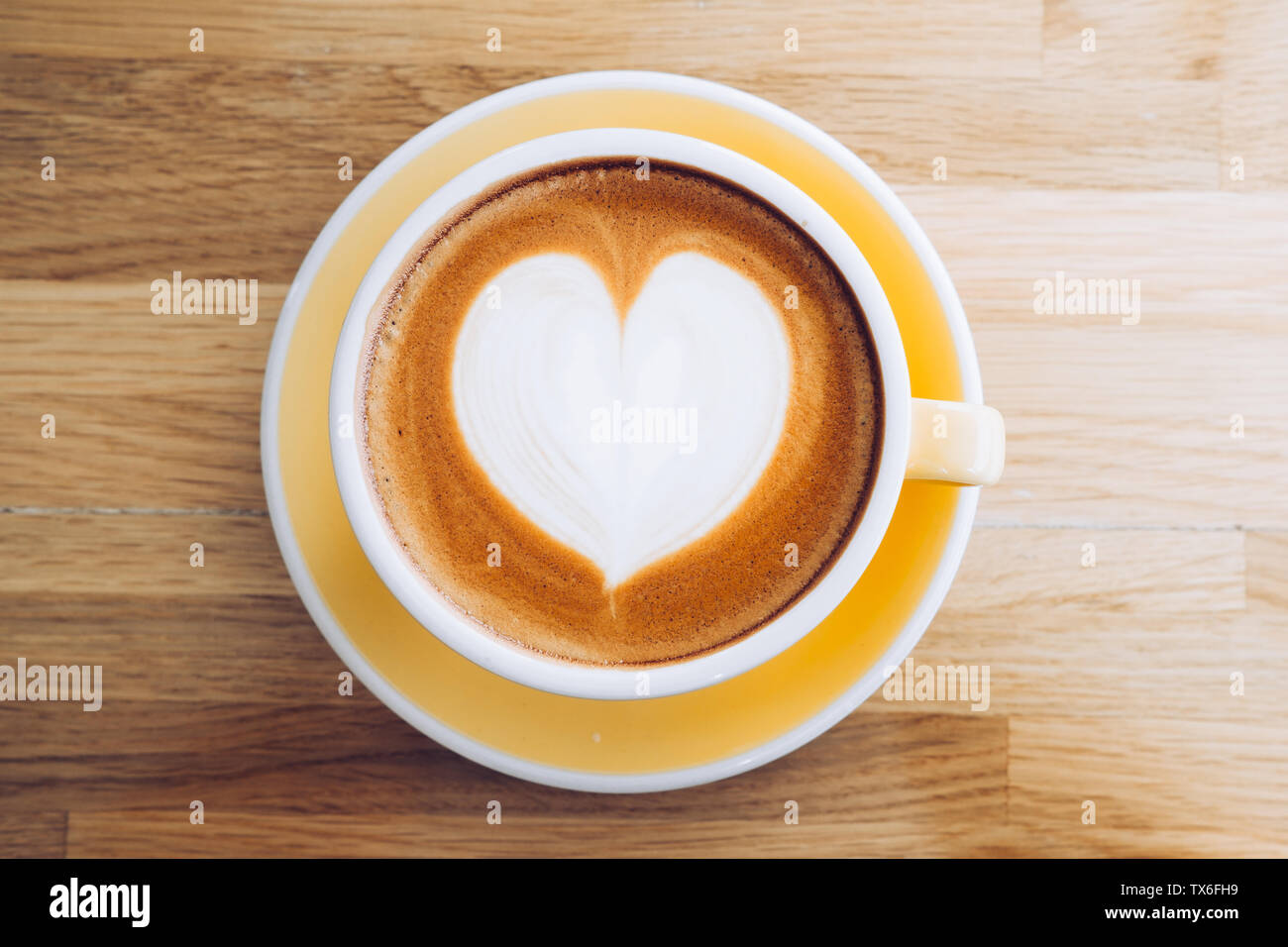 Blick von oben auf die heißen Cappuccino Tasse auf Holz- Fach mit Herz latte Kunst auf Holz Tisch im Cafe, Banner Größe Essen und Trinken Konzept. Stockfoto