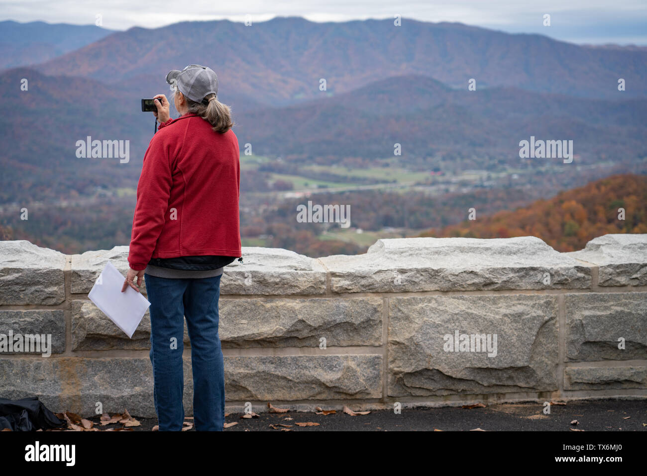 Eine ältere Frau mit einem Rucksack auf nimmt Bilder der Berge im Herbst. Stockfoto