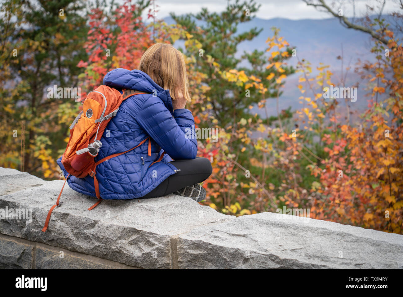 Eine ältere Frau mit einem Rucksack auf nimmt Bilder der Berge im Herbst. Stockfoto