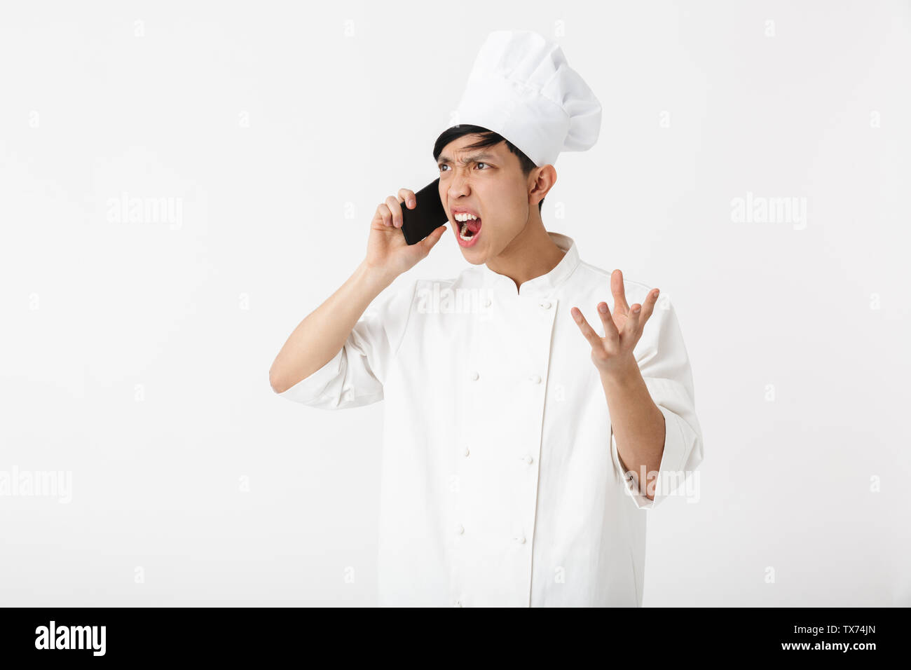 Bild gereizter chinesischen chief Mann in Weiß cook einheitliche und Kochmütze Gespräch am Handy auf weißem Hintergrund Stockfoto