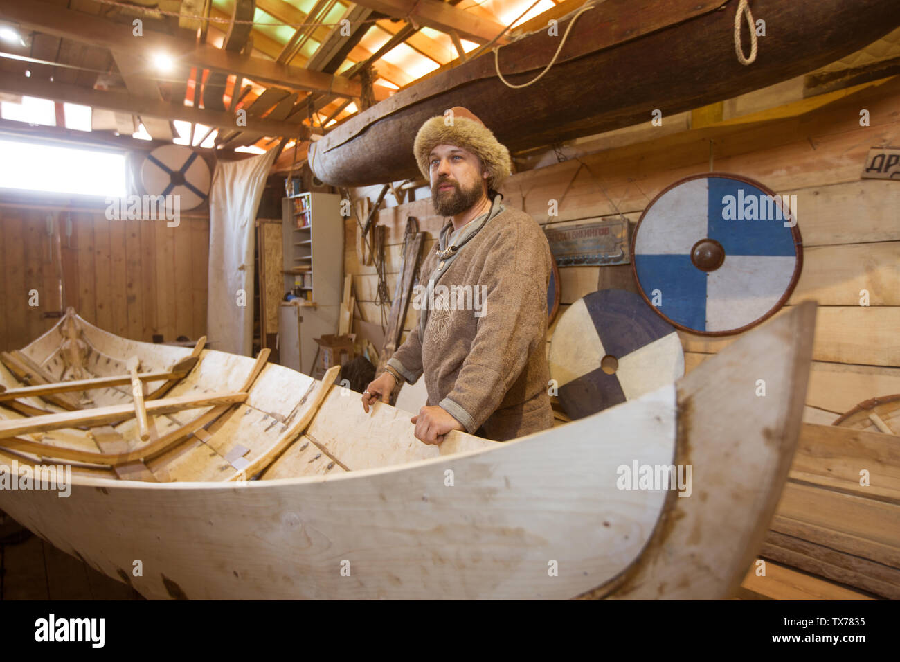 Handgefertigten Holz- Boot in der Scheune und reenactor in mittelalterlichen Kleidern Stockfoto