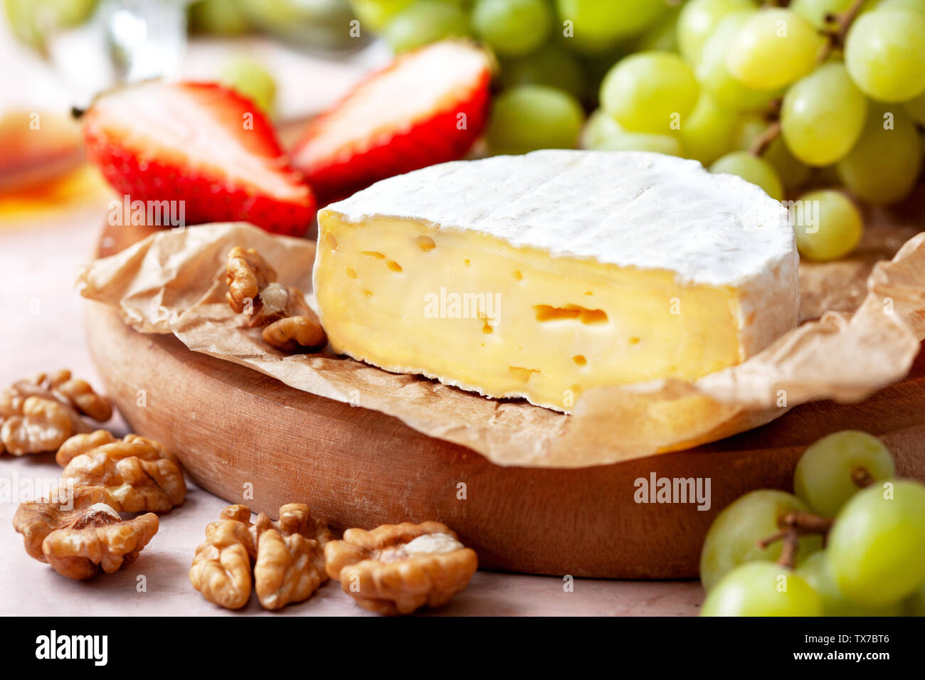 Camembert, Trauben, Nüsse, Erdbeeren auf einem Holzbrett closeup Stockfoto