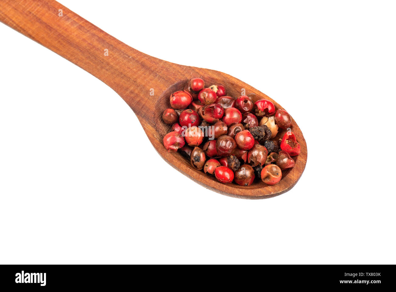 Rote Paprika Erbsen in hölzernen Löffel schließen bis auf weißem Hintergrund Stockfoto