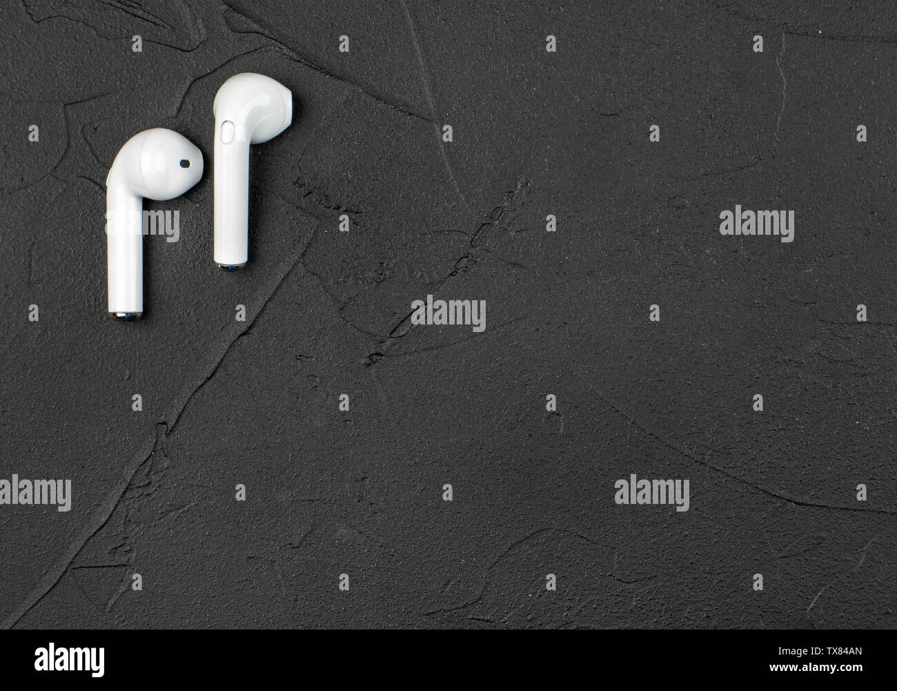 White kabellose Bluetooth® Kopfhörer auf dunklen konkreten Hintergrund, Ansicht von oben Stockfoto