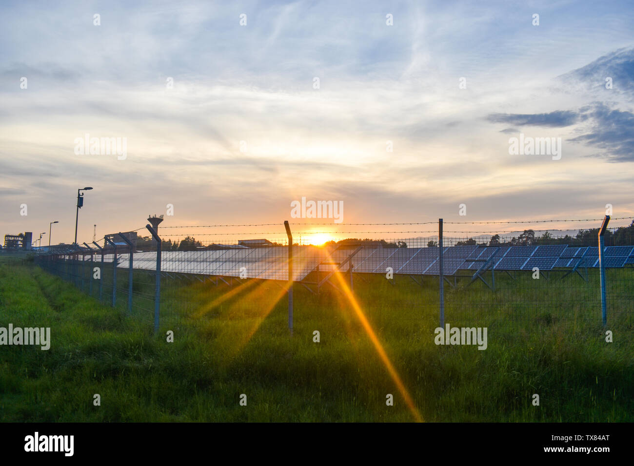 Sonnenuntergang über eine Photovoltaikanlage mit Photovoltaik-modulen für erneuerbare Energie auf dem Feld. Solar Power Generation Ausrüstung mit Europa gebaut Stockfoto