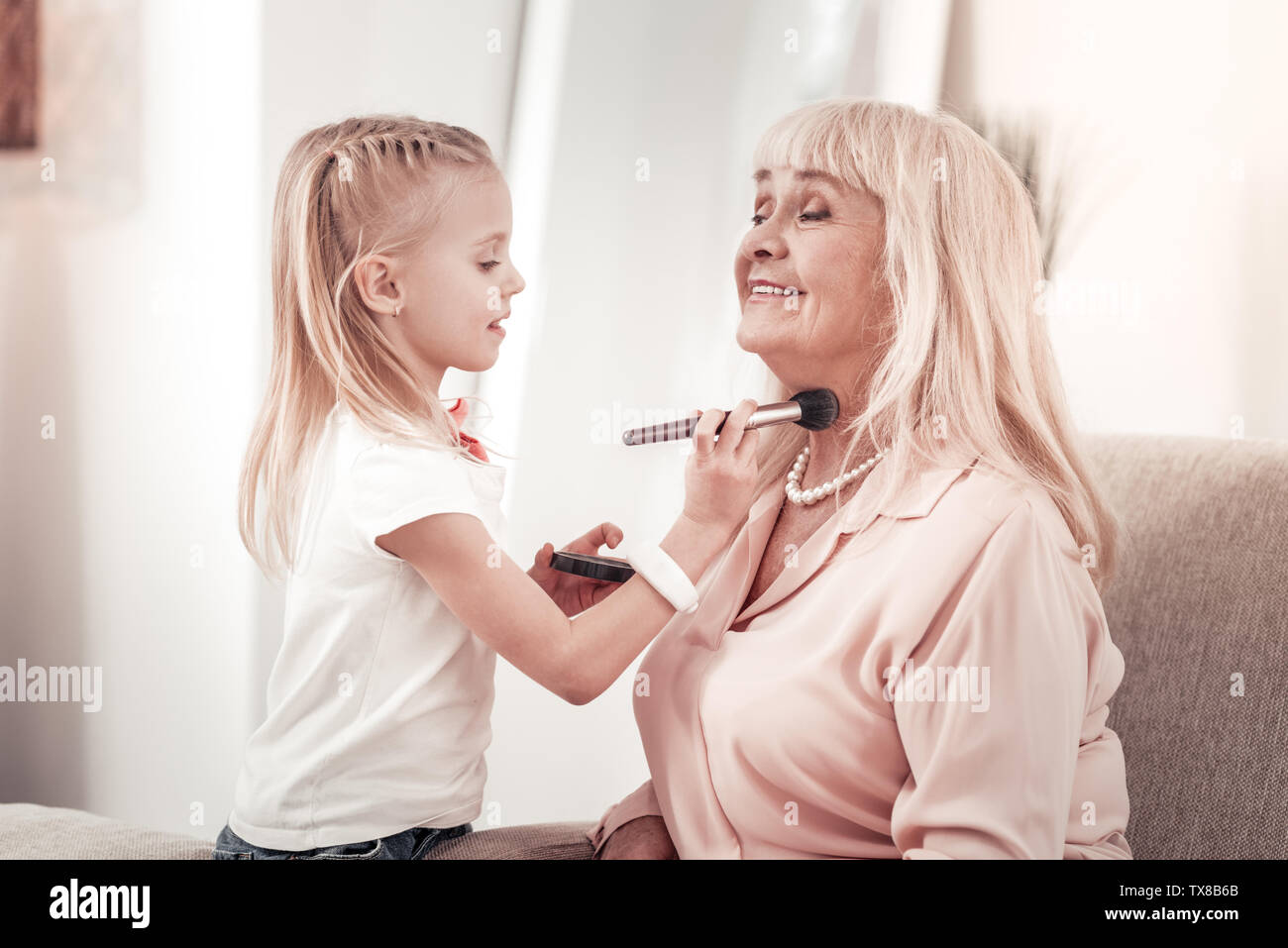 Elegante blonde Großmutter Gefühl zufrieden mit ihrer Enkelin Stockfoto