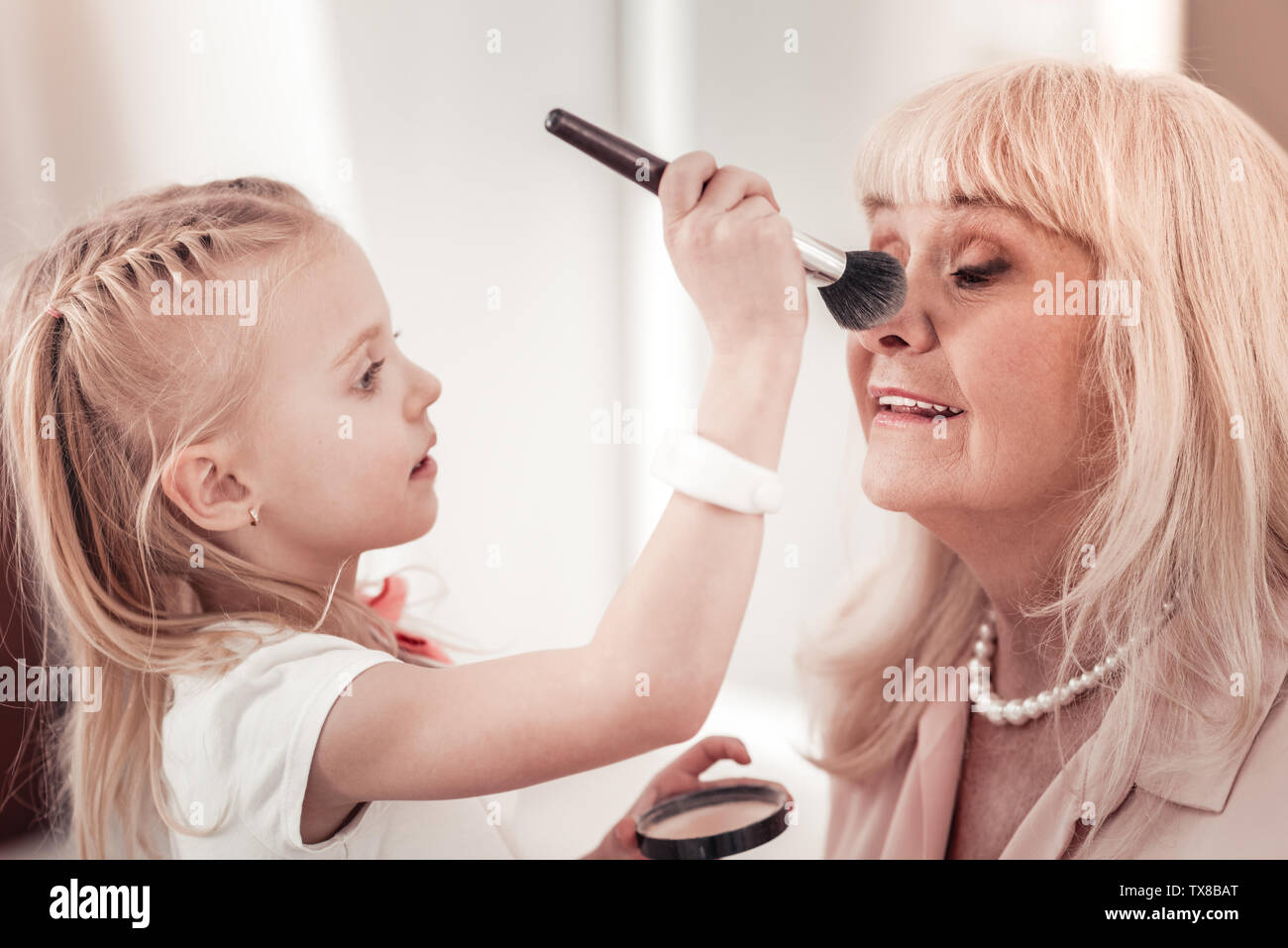 Erstaunlich kleines Mädchen, Make-up zu ihrer Großmutter Stockfoto