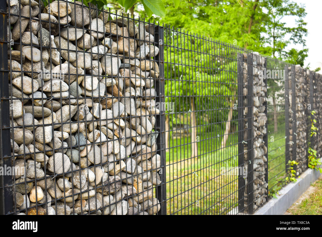 Textur der Steinmauer. Der Zaun aus Stein. Die steinwand ist rund mit schwarzem Stahl gebunden. Design Ideen, Hintergründe, Banner und ar machen Stockfoto