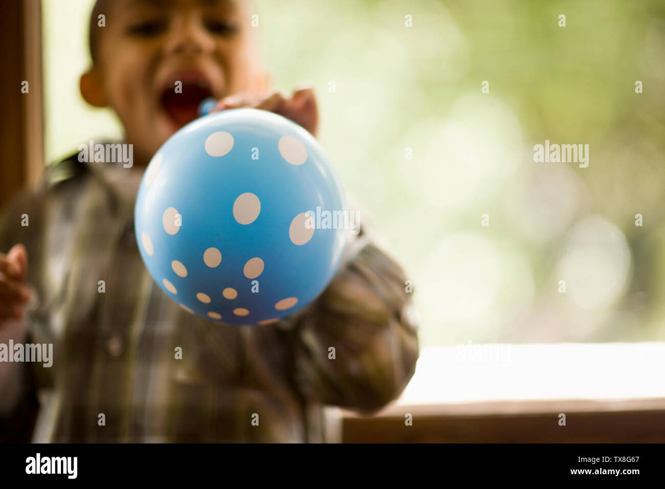 Porträt eines Jungen Sprengen eines Blue Polka-dot Ballon. Stockfoto