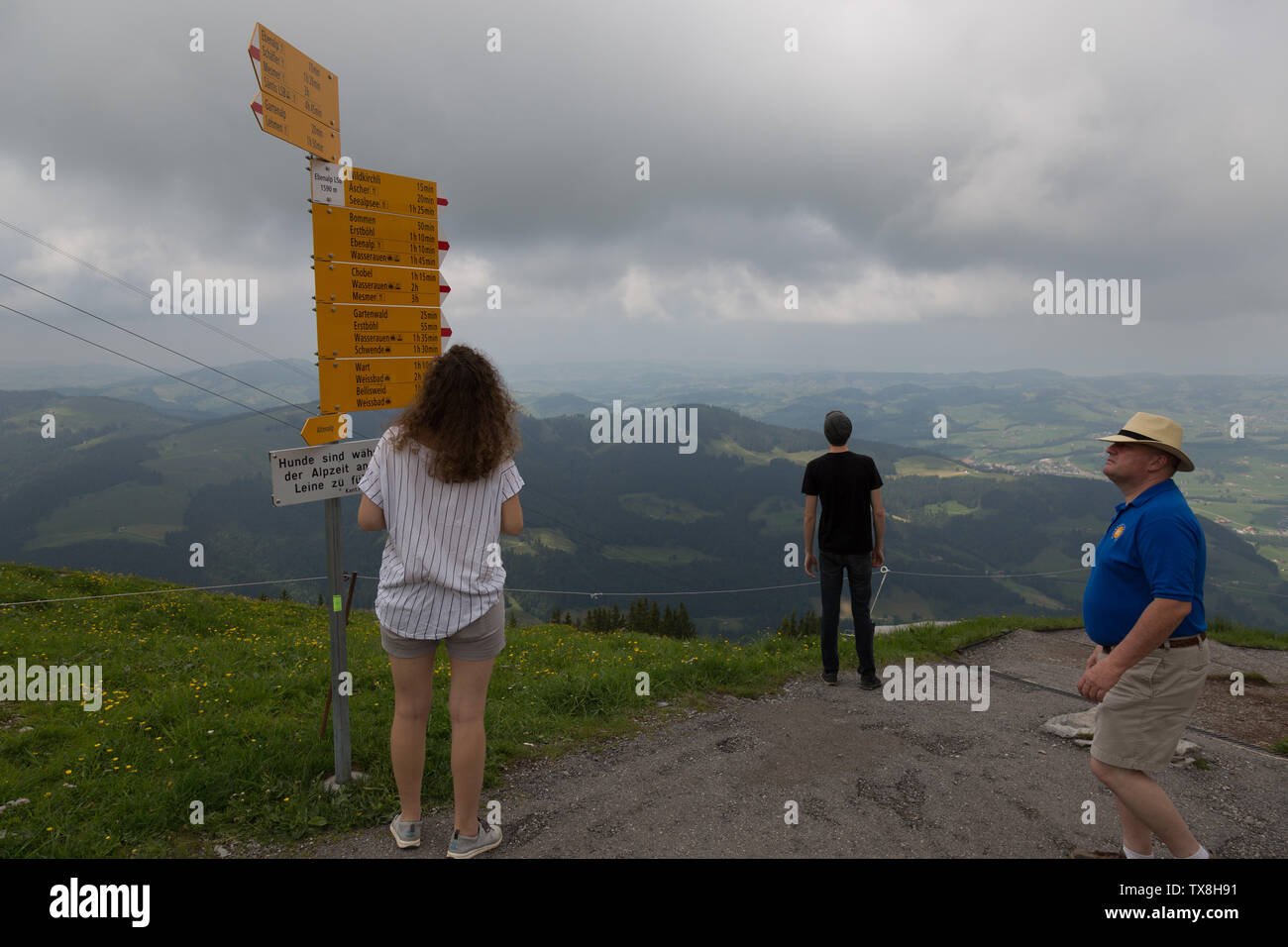 Verlorene Touristen, die an einem bewölkten Schweizer Tag auf dem Ebenalp in Appenzell, Schweiz, den Wegweiser für die Wegbeschreibung überprüfen. Stockfoto