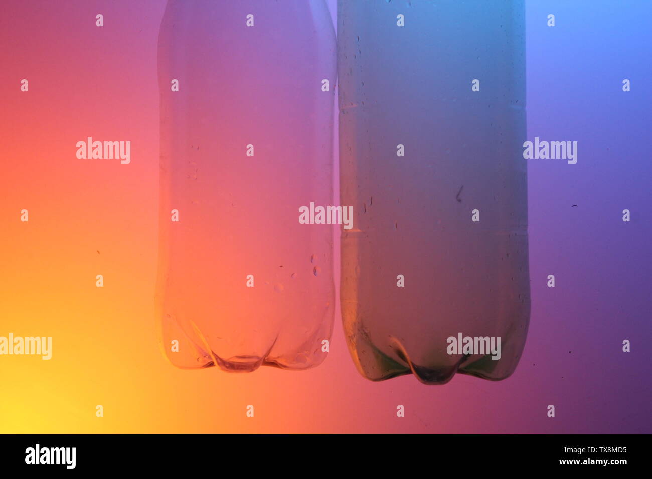 Nahaufnahme von klaren Flaschen auf einem farbigen Hintergrund mit künstlicher Beleuchtung Stockfoto