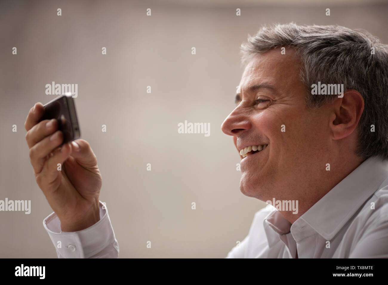 Reifen Geschäftsmann, Lächeln, da blickt er auf sein Handy. Stockfoto