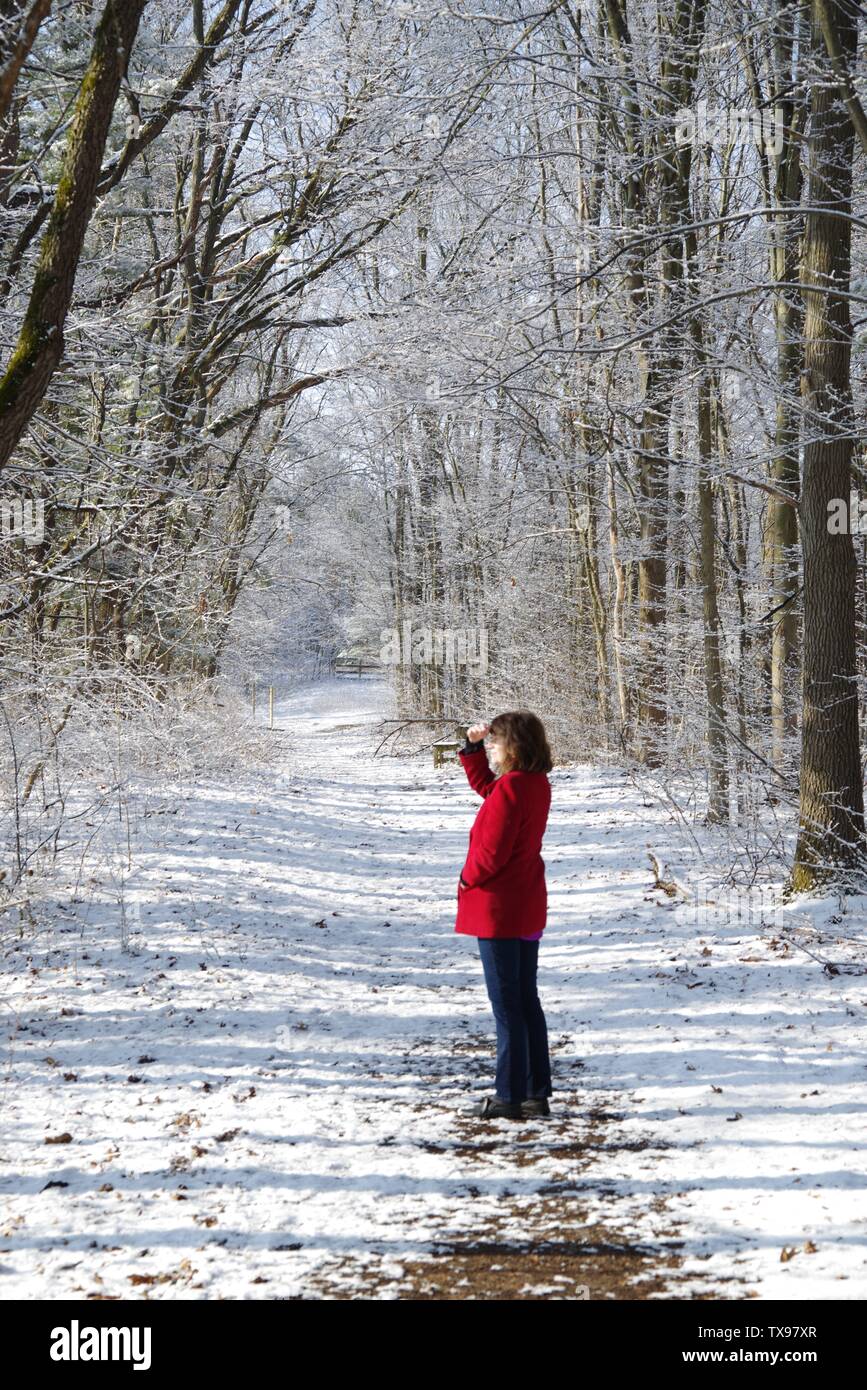 Eine Frau in Rot entlang eine winter Waldweg. Stockfoto