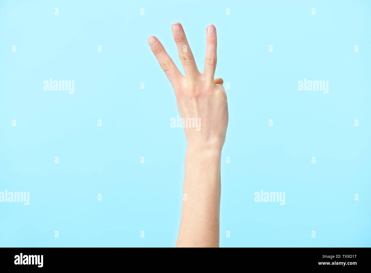 Menschliche Hand zeigt die Nummer drei, auf blauem Hintergrund isoliert Stockfoto