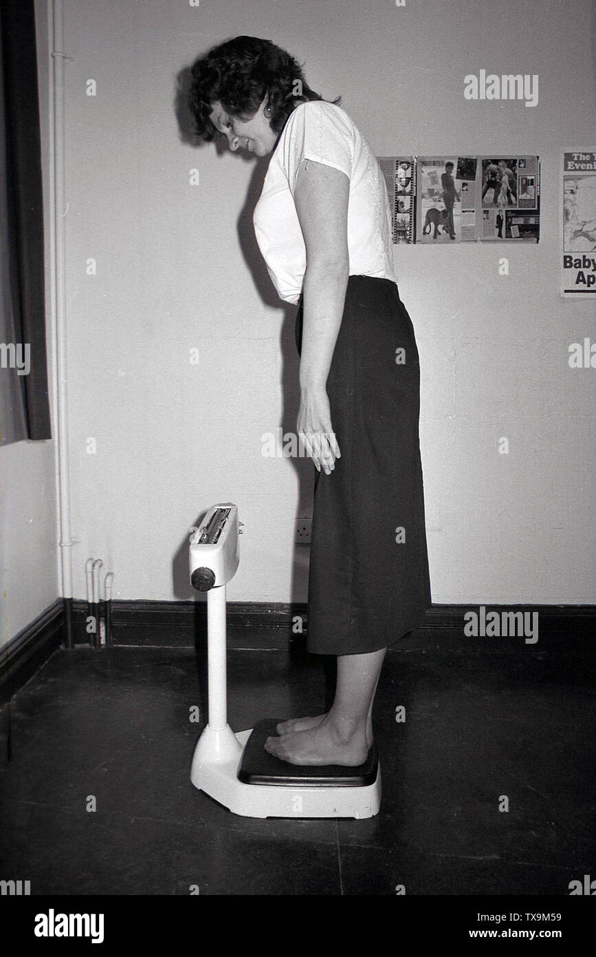 1980, in einem Zimmer, einer Dame in Barfuss stehend auf eine Reihe von mechanischen, Waagen, die Messung, England, UK zu sehen. Stockfoto