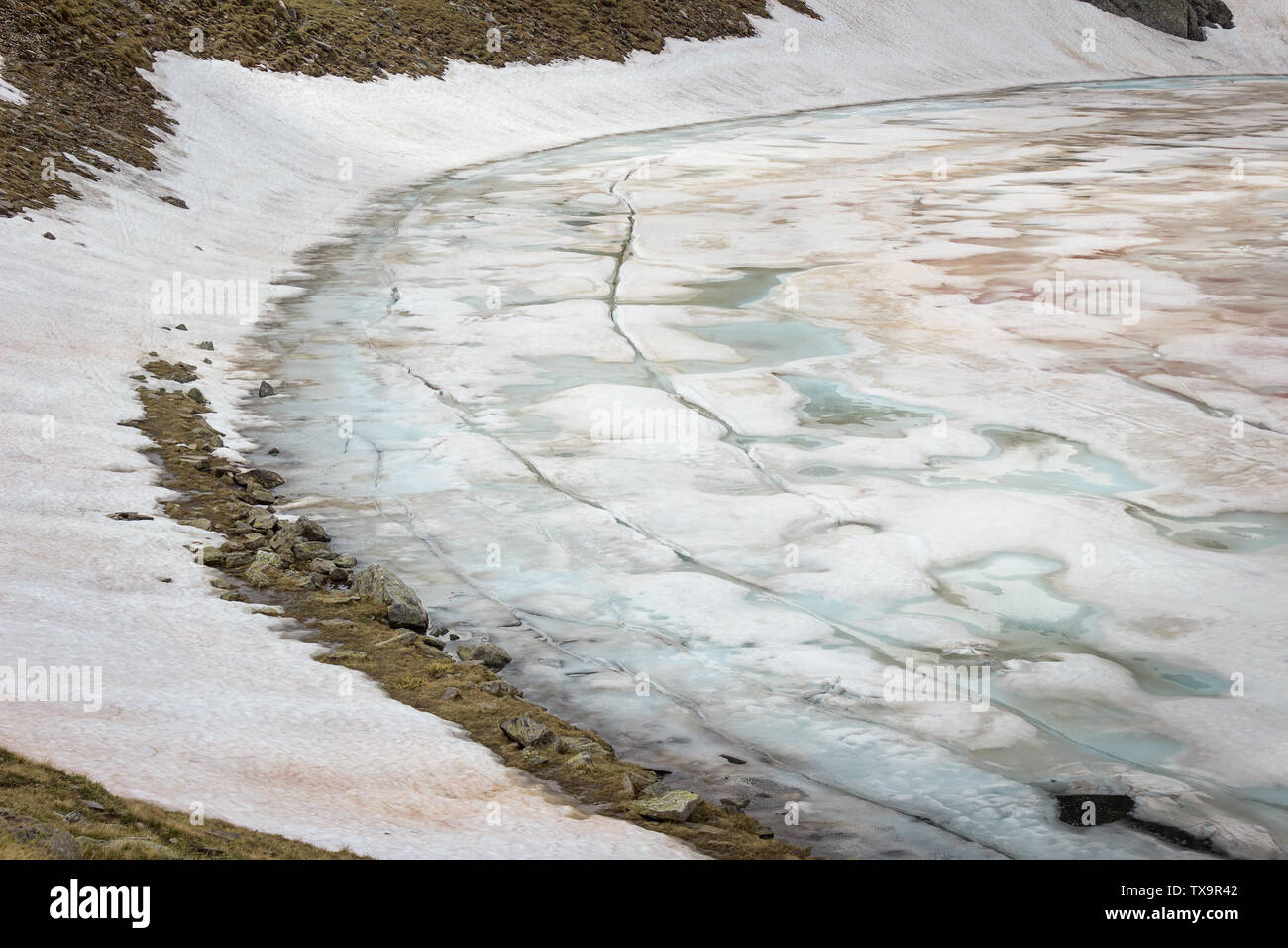 Nahaufnahme der Eye See auf Rila Gebirge in Bulgarien, einem der Seen der berühmten Tour von sieben glazialen Rila Seen, bedeckt von bunten, gebrochene Eis Stockfoto