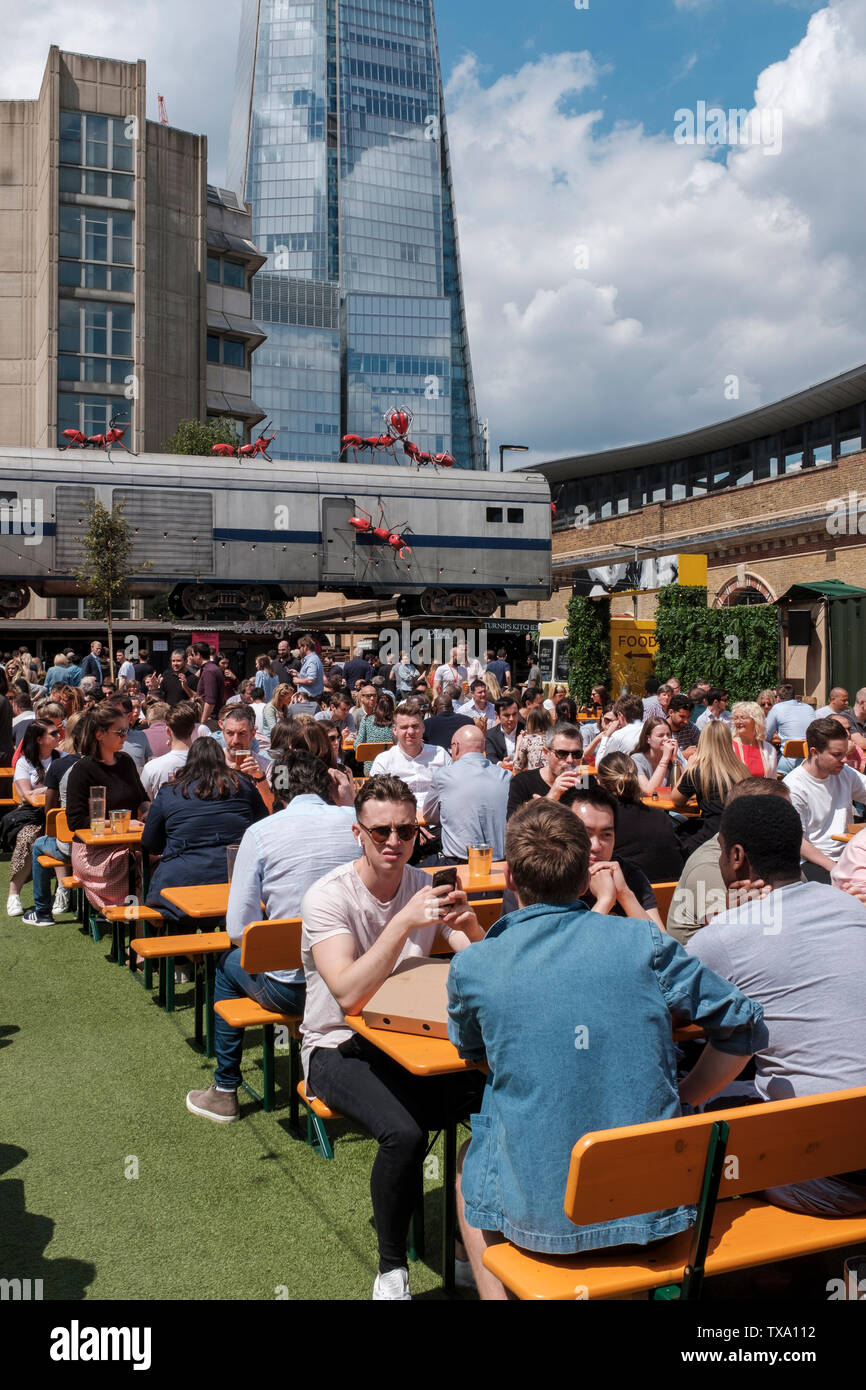 UK, London - Menschen zu essen, an einem sonnigen Tag. Essig Yard ist ein Städtischer Garten geöffnet sieben Tage die Woche, mit Ständen, Vintage Kleidung und Antiquitäten t Stockfoto