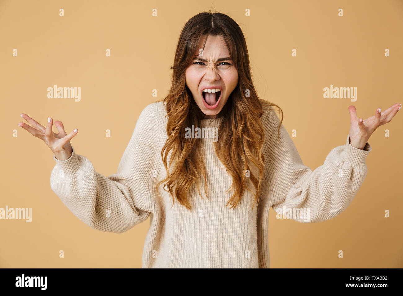 Schöne mad junge Frau trug Pullover stehend über beigen Hintergrund isoliert, schreien Stockfoto