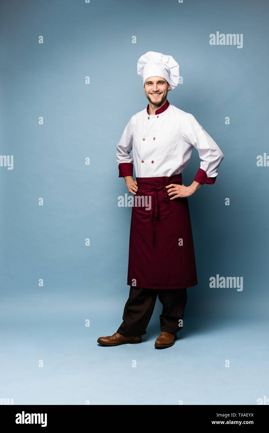 Volle Länge Portrait von Heiter fröhlichen Koch Kochen mit Stoppeln in Baskenmütze und weißen Outfit an Kamera suchen isoliert Stockfoto