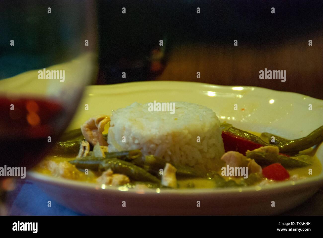 Asiatische typisches Essen mit weißer Reis und Curry mit Kokosmilch und würzige Creme serviert mit Gemüse und Rotwein Stockfoto