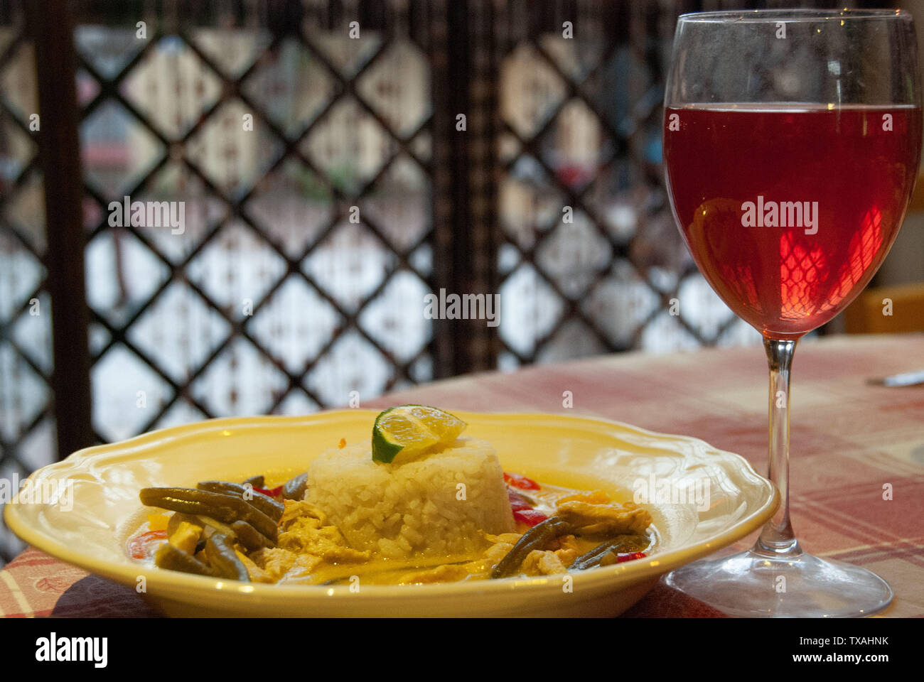 Asiatische typisches Essen mit weißer Reis und Curry mit Kokosmilch und würzige Creme serviert mit Gemüse und Rotwein Stockfoto