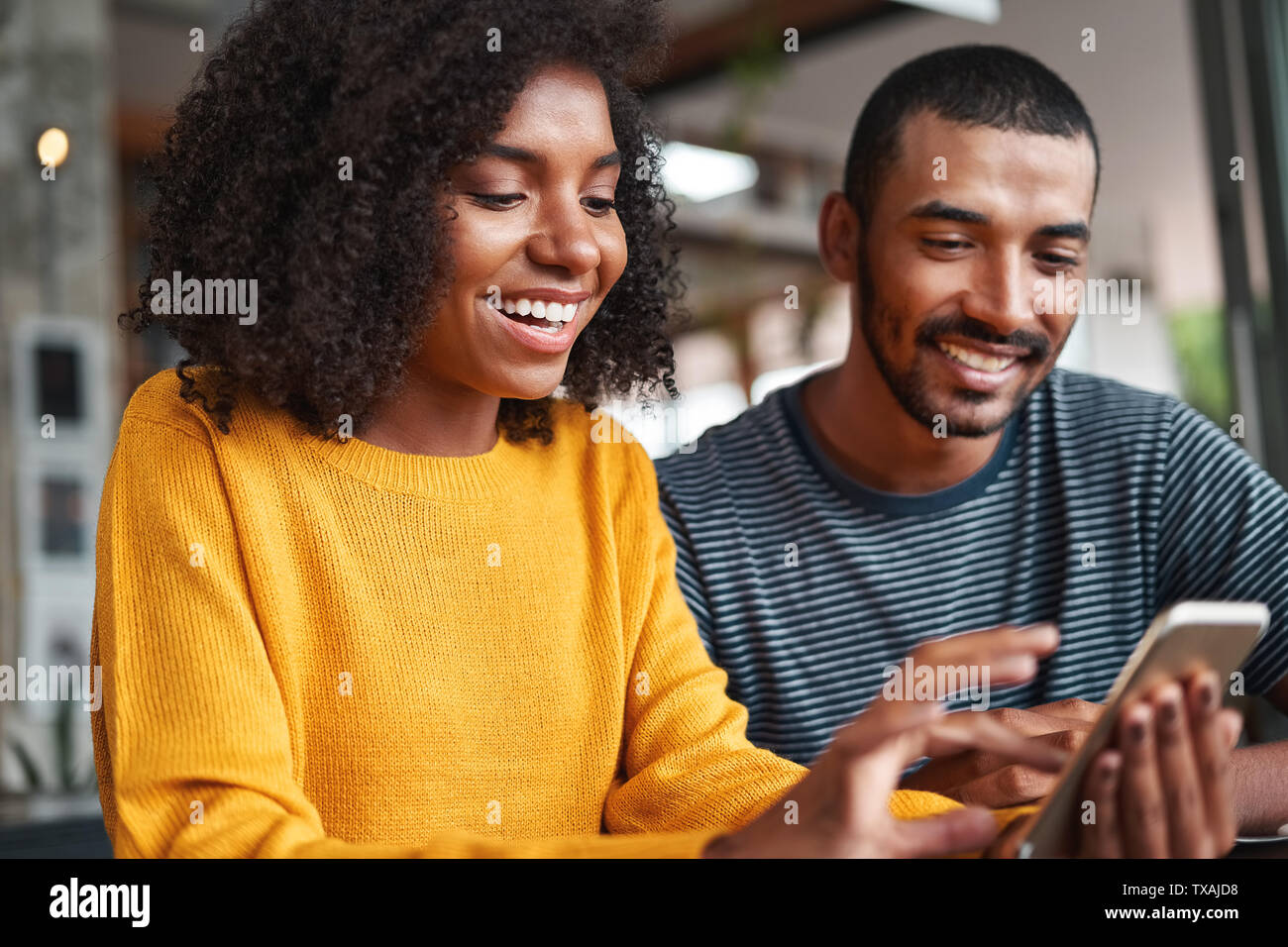 Fröhlicher junger Paare an Smartphone suchen Stockfoto