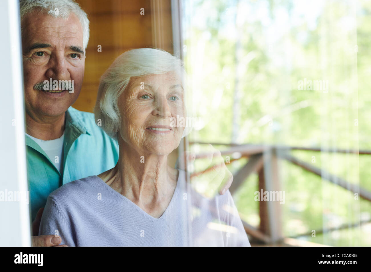 Positive reifer Mann und Frau, die durch die Fenster Stockfoto