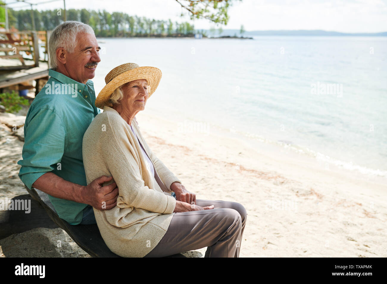 Senior romantischen Mann und Frau sitzt am Strand Stockfoto
