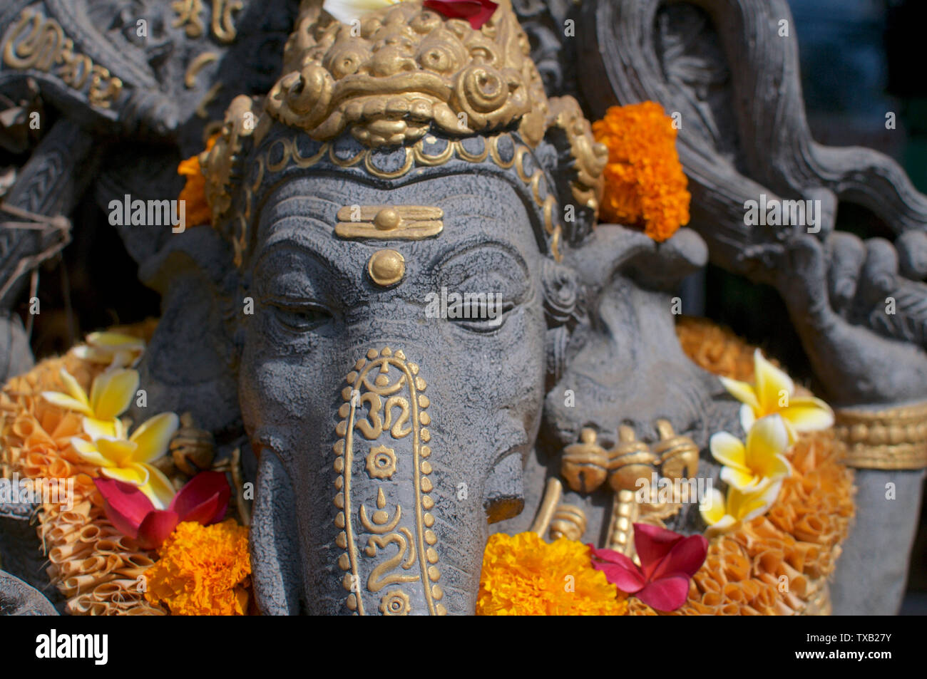 Vorderen Kopf geschossen von einem schönen Ganesha Stein Statue mit Ringelblume Blumen dekoriert und vor einem Spa Eingang in Ubud, Bali - Indonesien Stockfoto