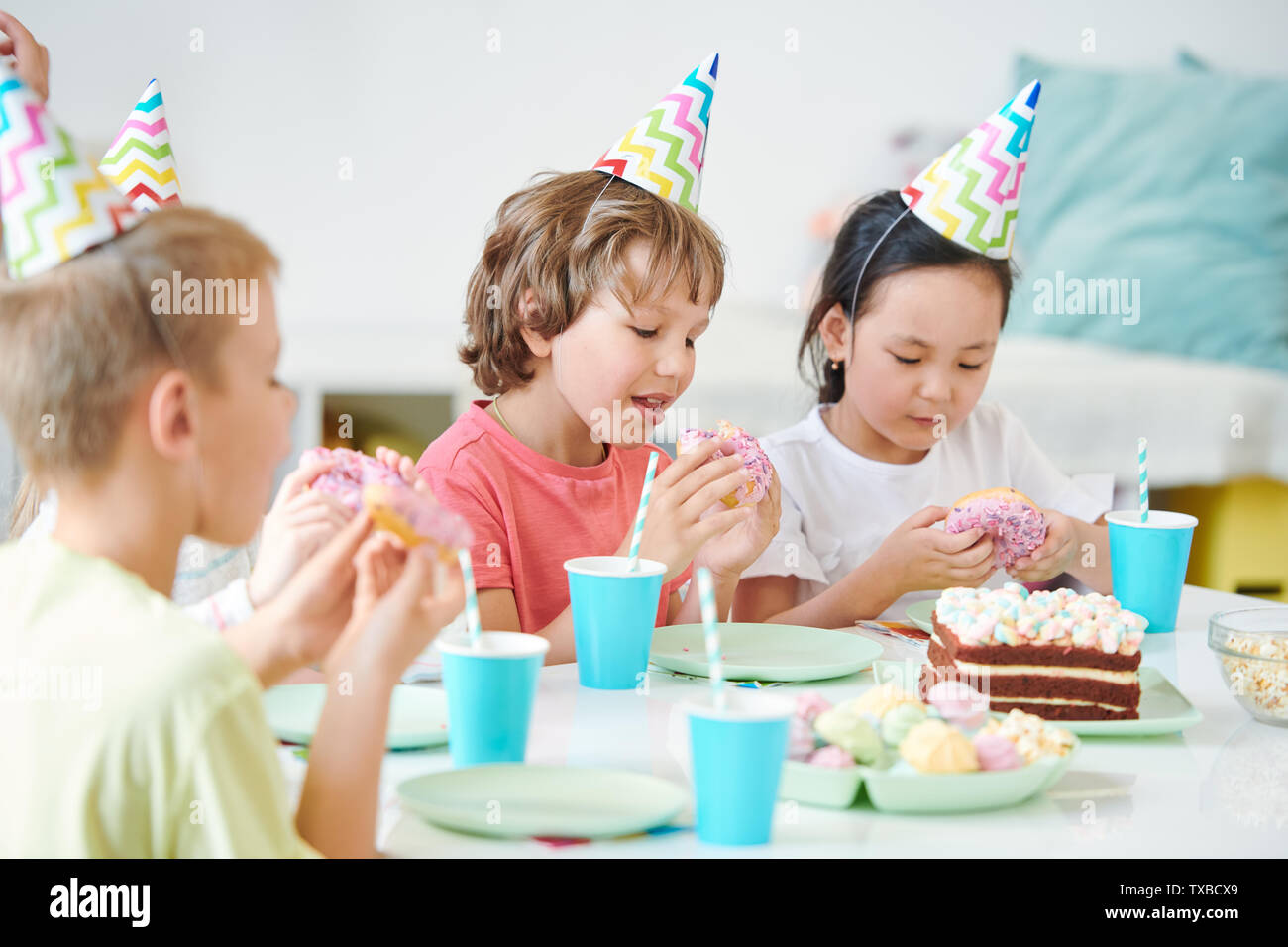 Gruppe der hungrigen Kinder essen glasierte Krapfen mit Streuseln Stockfoto