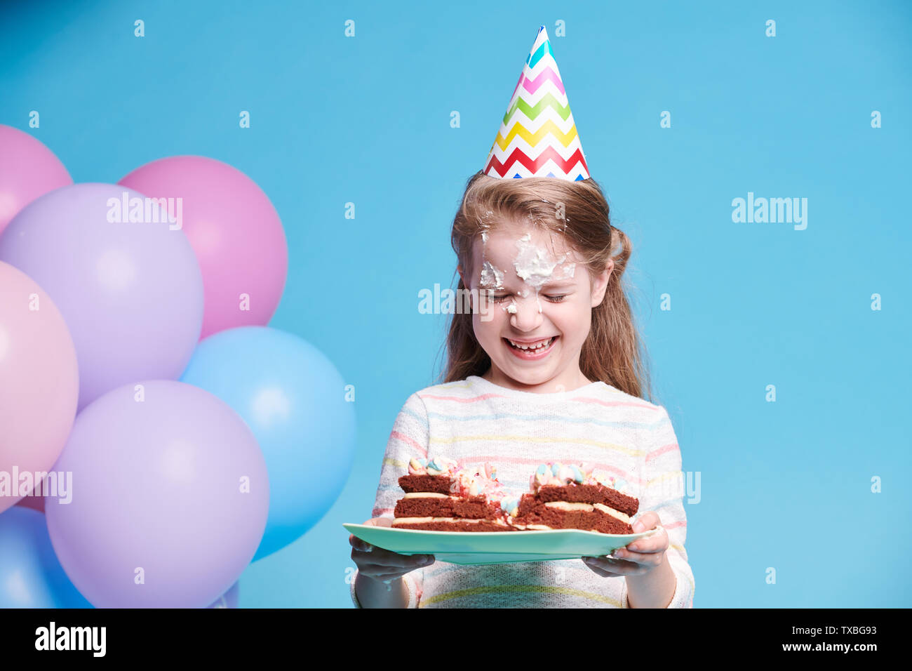 Niedlich lustig Mädchen lachend, während Sie die Platte mit Geburtstagstorte Stockfoto
