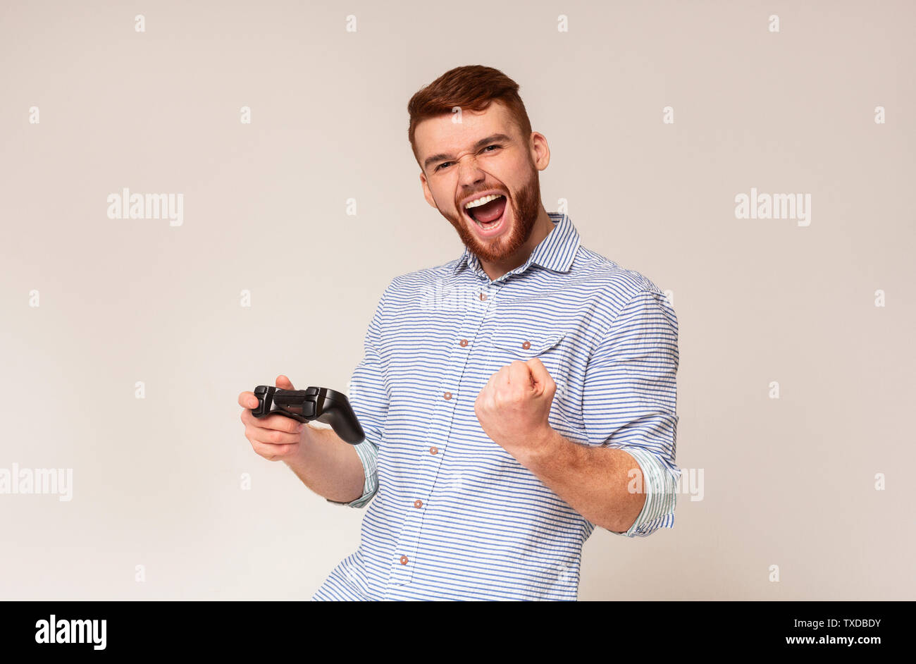 Sieg Geschmack. Jungen Kerl gewinnen video spiel und glücklich fühlen in Studio Hintergrund, Panorama, freier Speicherplatz Stockfoto