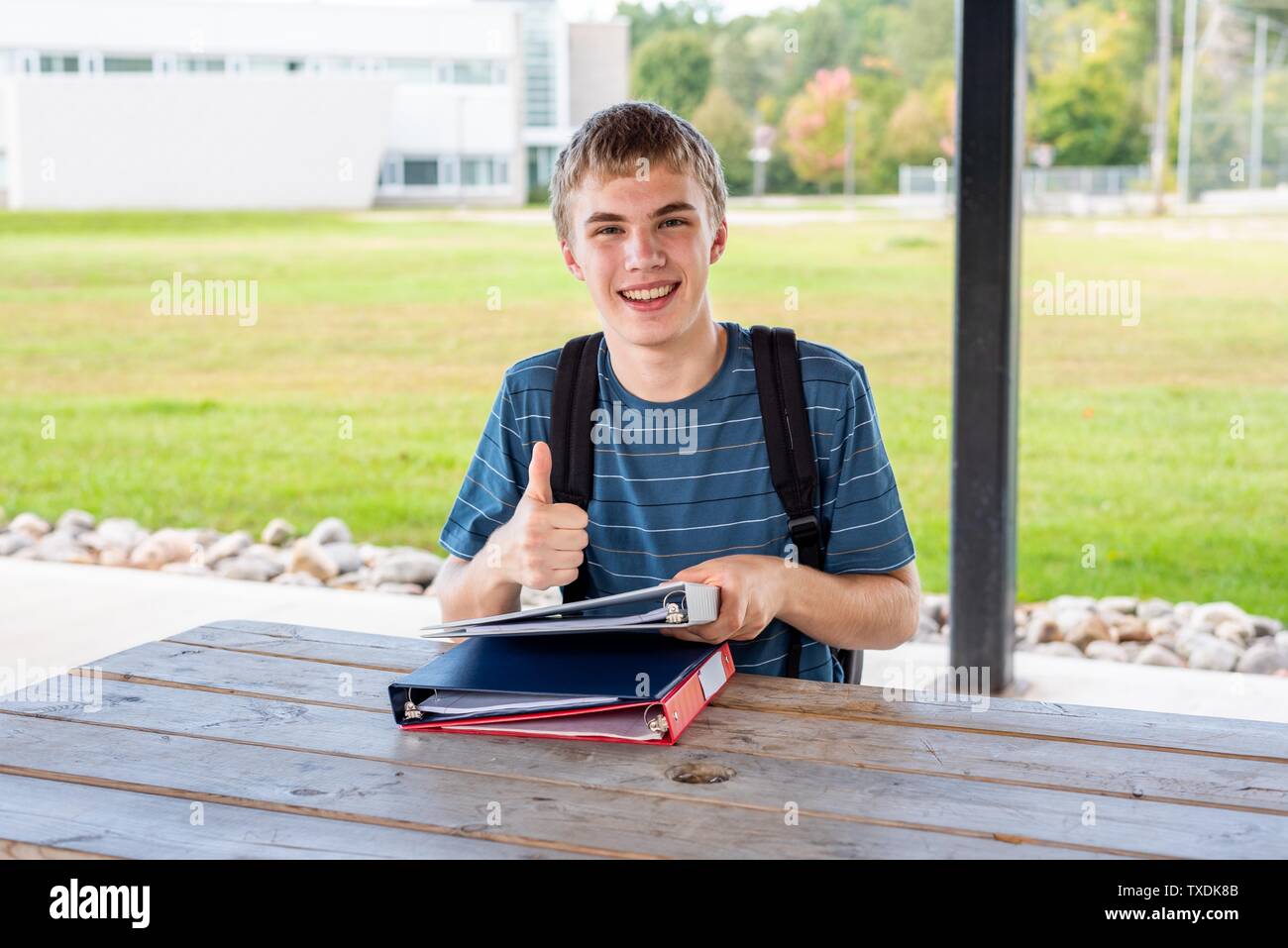 Happy Teenager seine Hausaufgaben im Freien tun neben einer Schule. Stockfoto